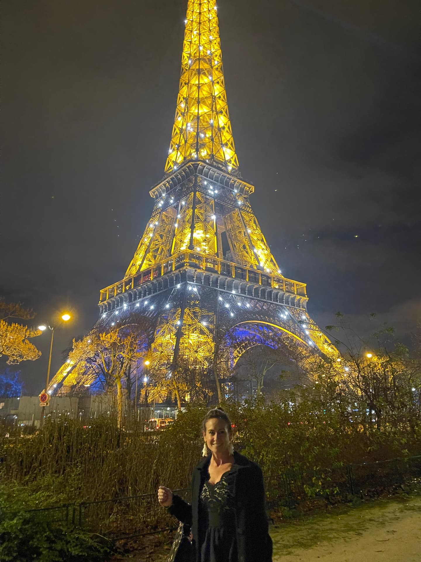 Jamie Leigh in front of the illuminated Eiffel Tower at night in Paris, France