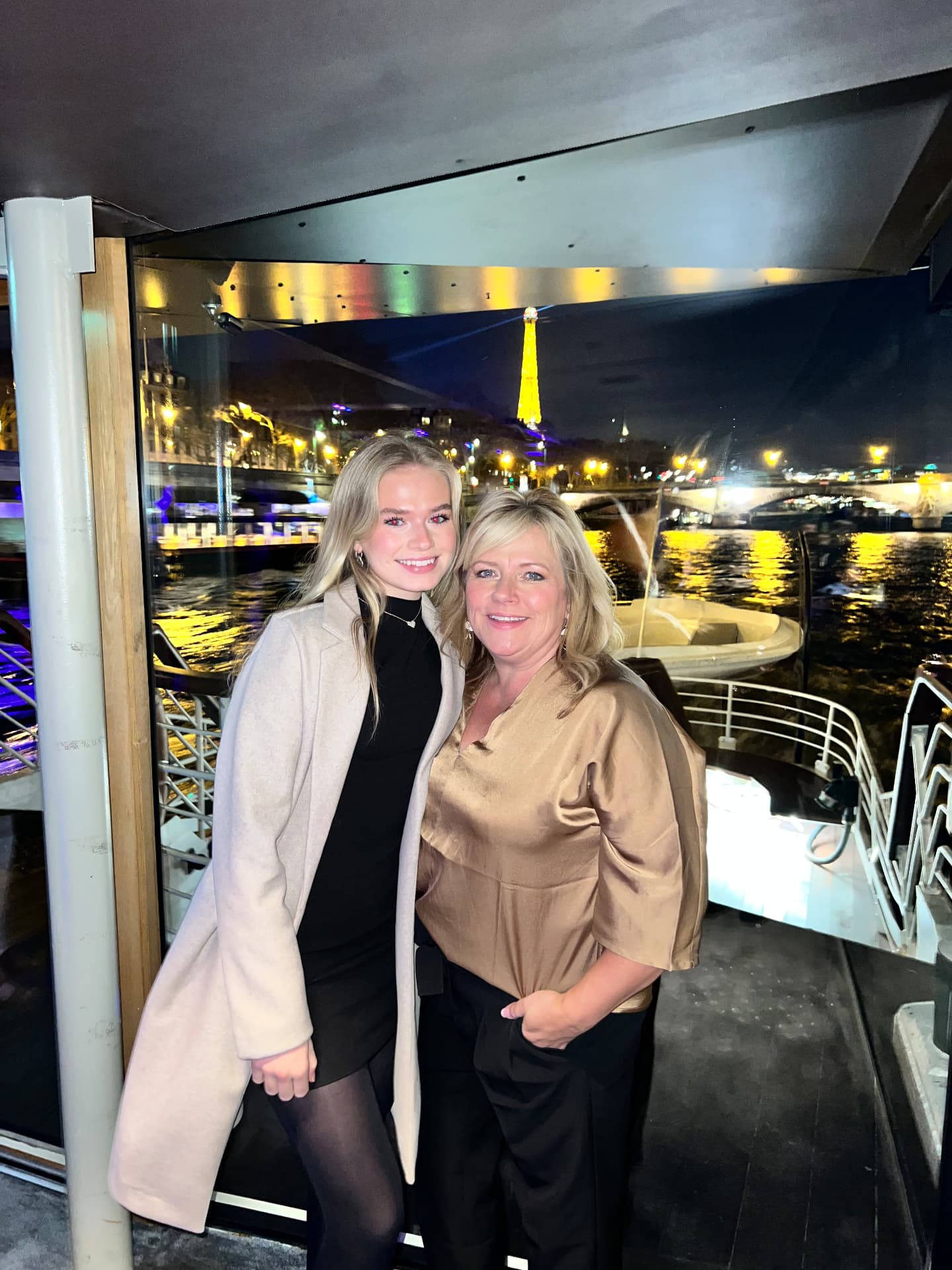 Two women aboard a Seine dinner cruise with the Eiffel Tower behind them