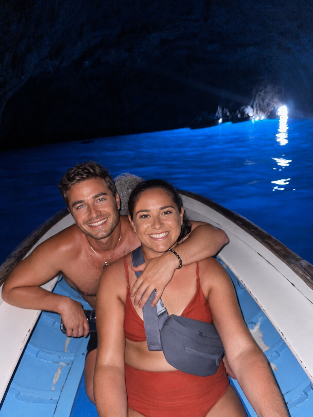 Couple together in a boat inside a glowing Blue Grotto sea cave