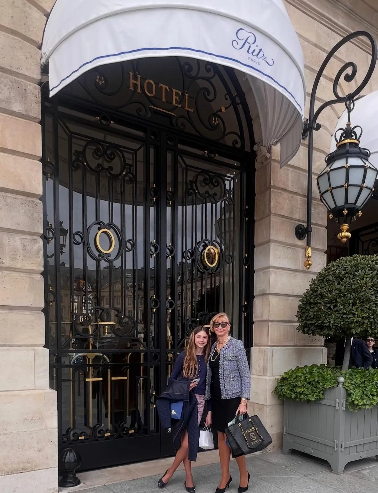 Mother and daughter outside the iconic wrought-iron entrance of the Ritz Paris on Place Vendôme