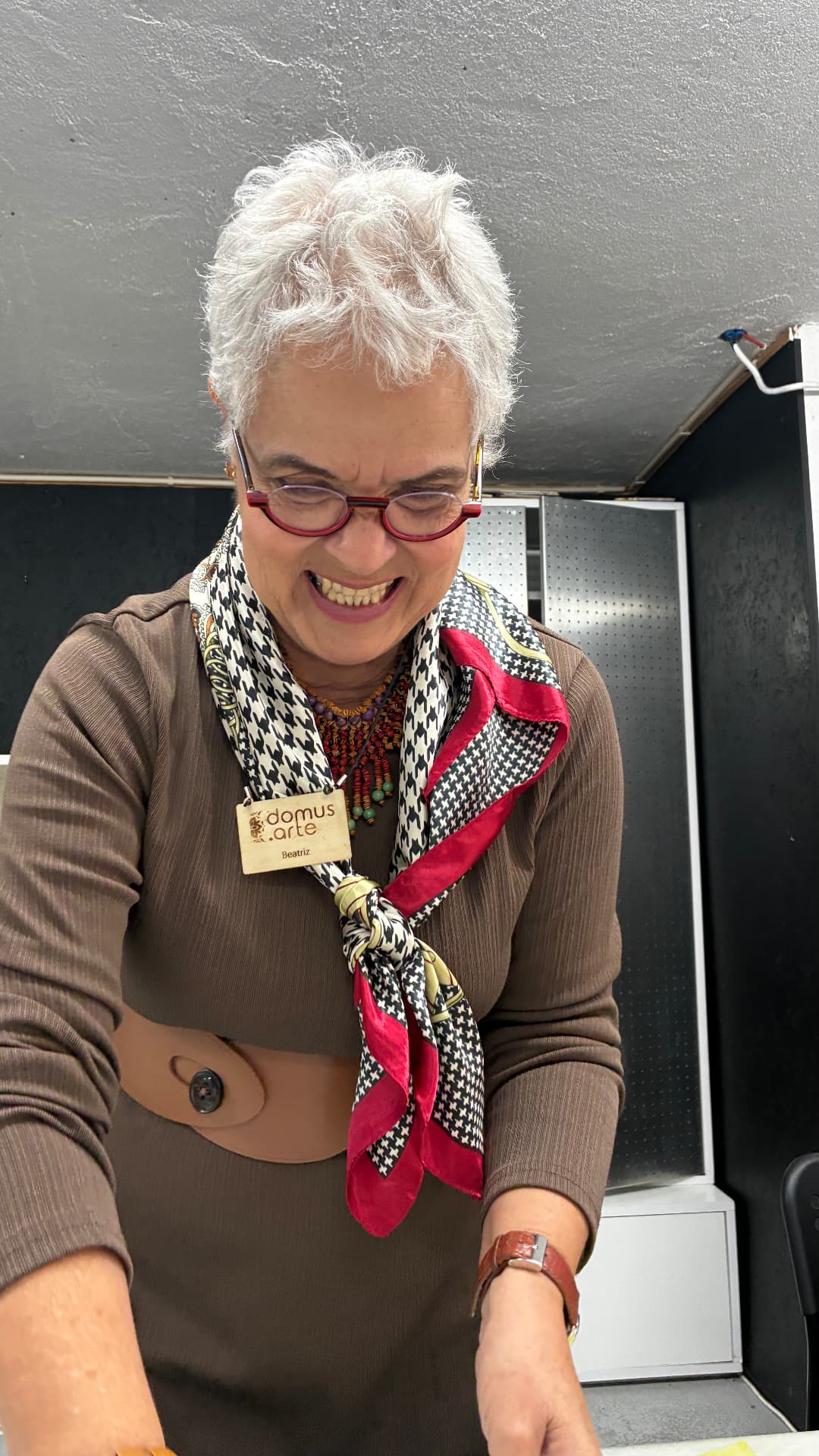 A smiling woman at a Portuguese tile-painting workshop holding her finished azulejo