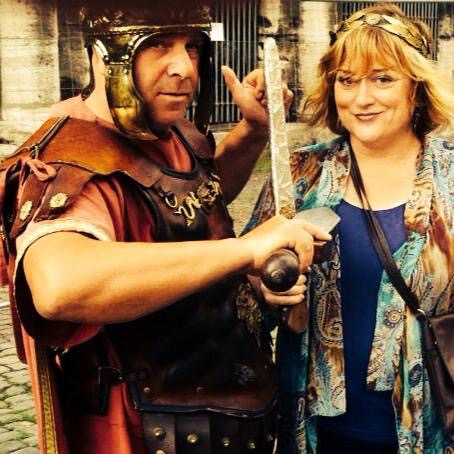 Jamie Leigh beside the Colosseum in Rome, Italy, with a costumed Roman centurion