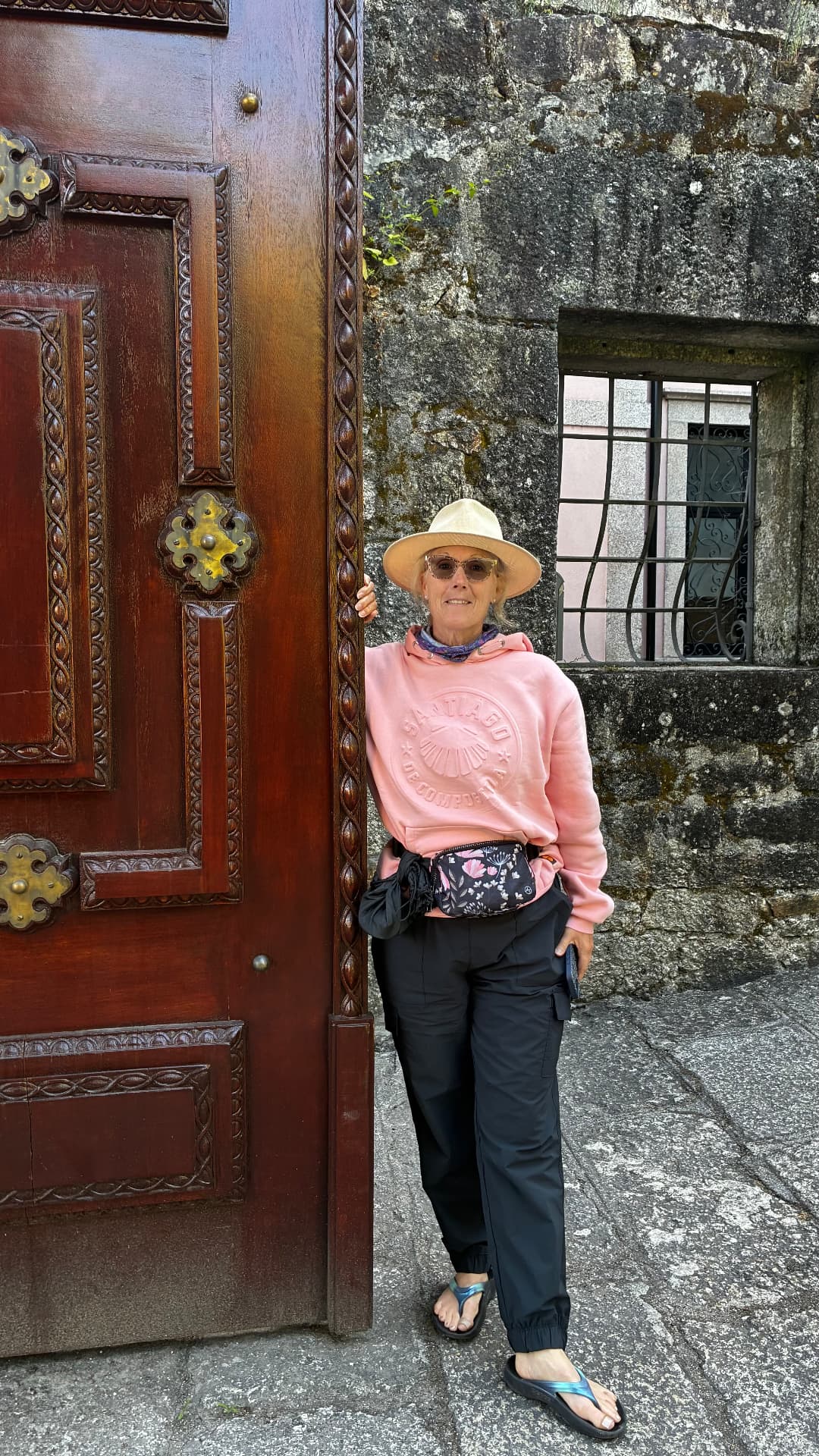 Traveler beside a carved wooden doorway in a Portuguese stone alley