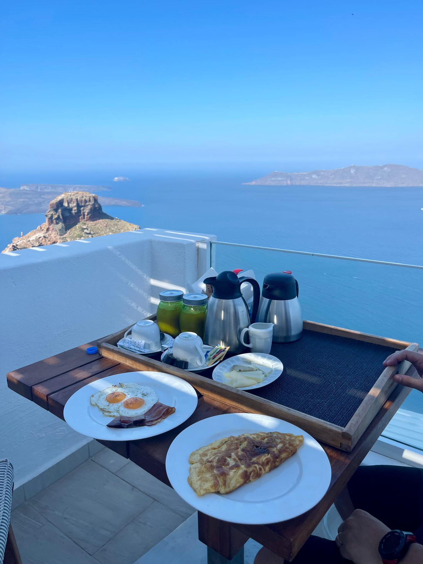 Breakfast table set above the sea with a wide Greek island view