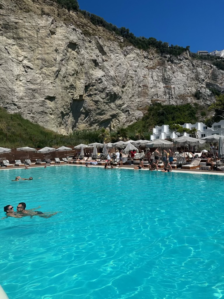 Couple in a cliffside beach club pool in Italy