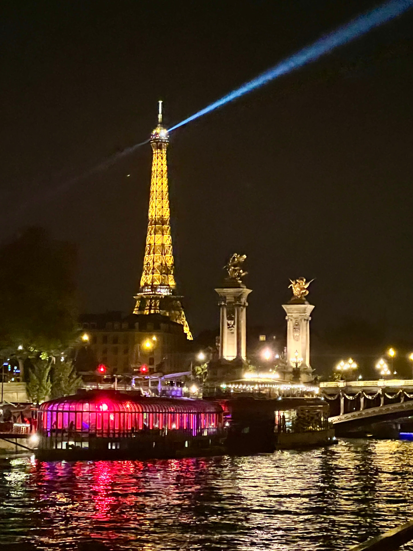 Eiffel Tower lit at night above the Seine River in Paris
