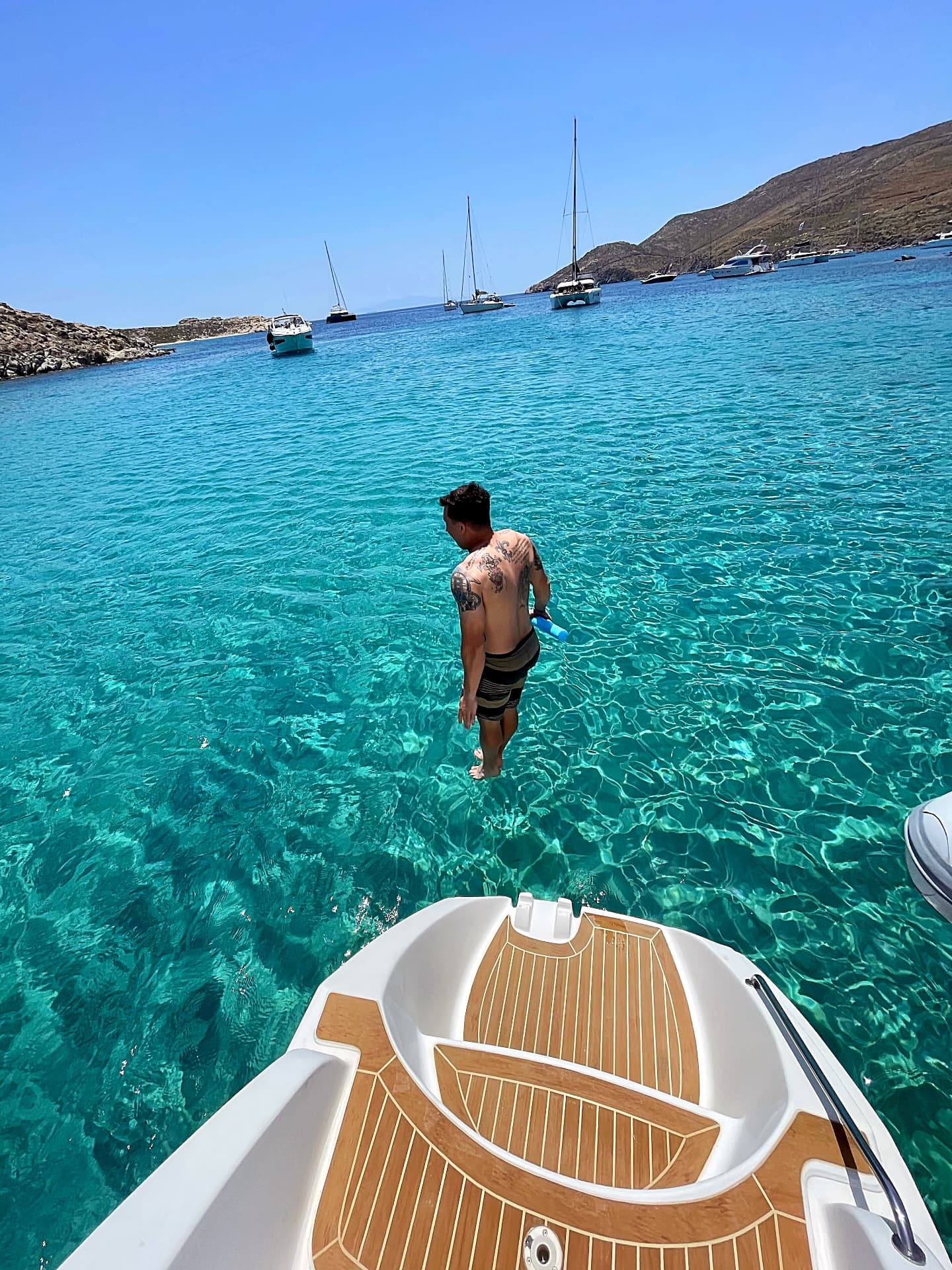 Swimmers in a clear turquoise cove on the coast of Mykonos