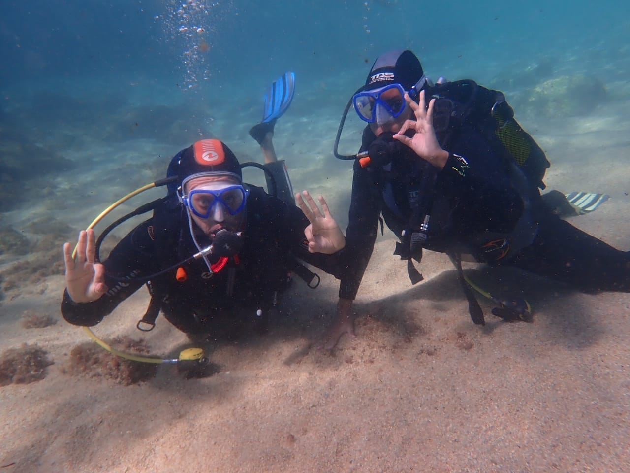 Couple scuba diving together over sandy Mediterranean seabed