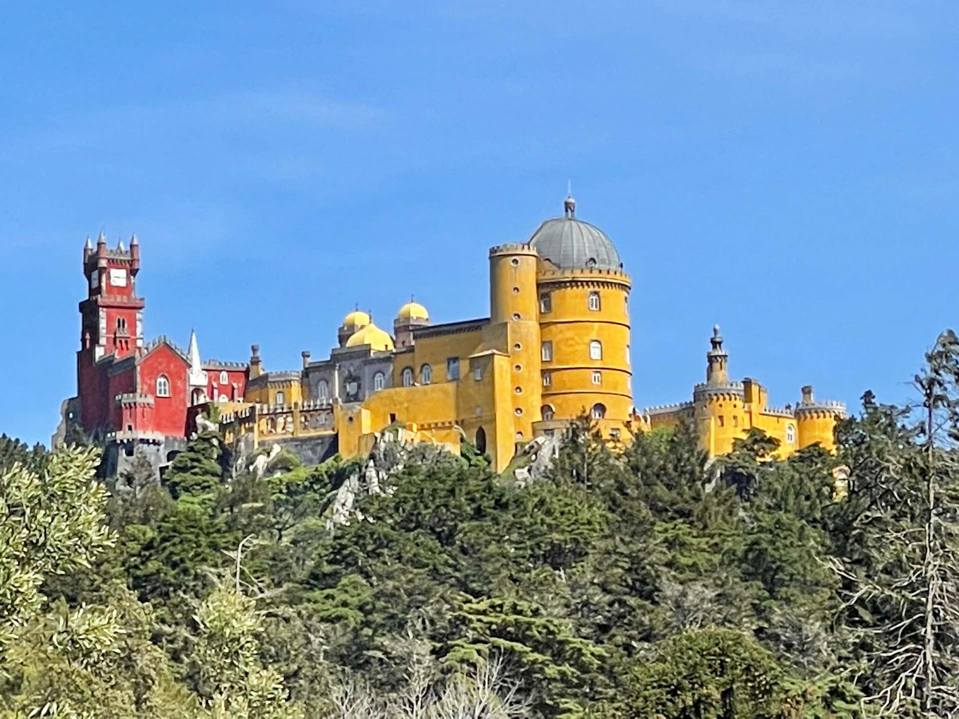 The red and yellow towers of Pena Palace rising above the forested hills of Sintra