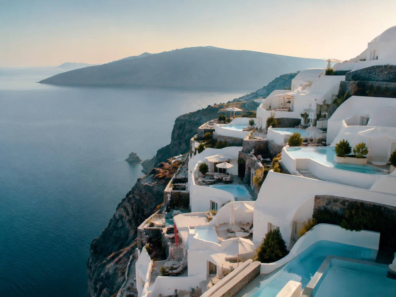 Terraced whitewashed luxury hotel suites with small pools on the Santorini caldera cliff